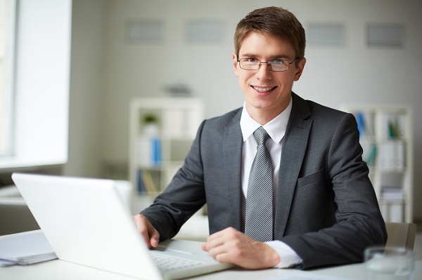 Smiling businessman in suit working with laptop in office